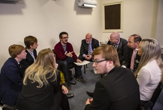 9 security professionals gathered around discussing ideas during a workshop.