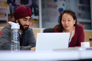 two apprentices sitting at table looking at laptop