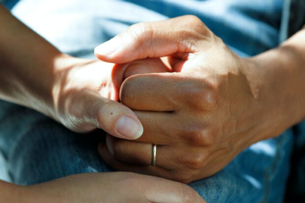 A hand clasping another hand indicating comfort and support